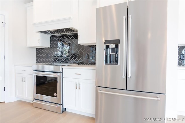 kitchen featuring appliances with stainless steel finishes, light countertops, premium range hood, white cabinetry, and backsplash