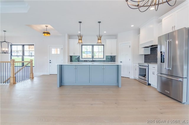 kitchen with appliances with stainless steel finishes, an inviting chandelier, light countertops, white cabinetry, and backsplash