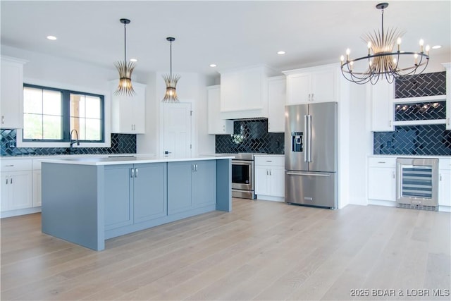 kitchen with stainless steel appliances, beverage cooler, white cabinets, and tasteful backsplash