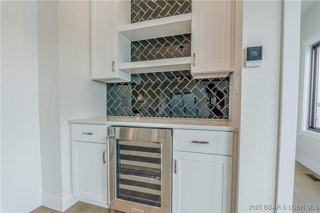 bar featuring beverage cooler, visible vents, decorative backsplash, baseboards, and a bar