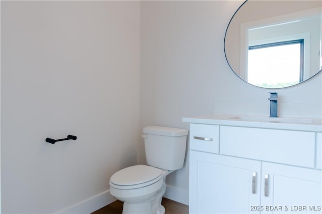 bathroom featuring baseboards, vanity, toilet, and wood finished floors