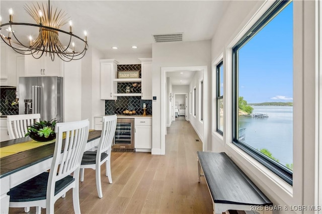 325 Mission Bay Dr, Camdenton, MO 65020 - dining space featuring a dry bar, visible vents, a chandelier, beverage cooler, and a water view