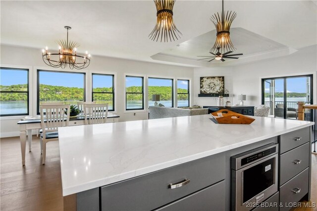 325 Mission Bay Dr, Camdenton, MO 65020 - kitchen featuring a notable chandelier, a tray ceiling, gray cabinetry, light stone counters, and open floor plan
