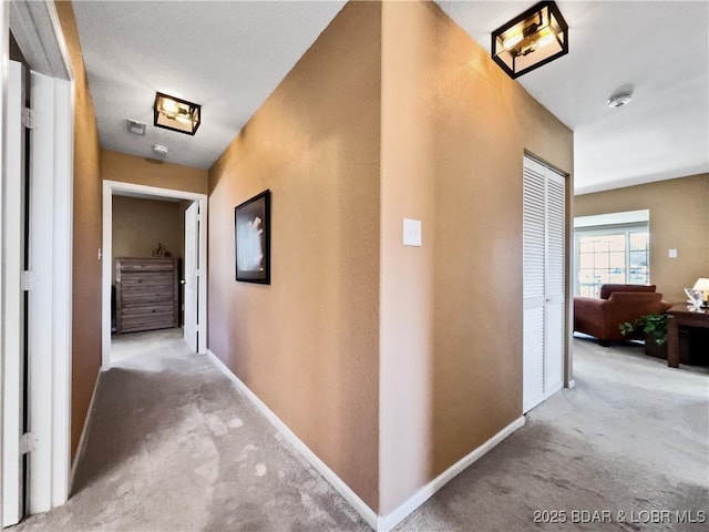 hall featuring carpet and baseboards