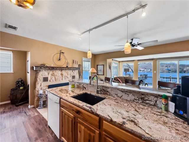 kitchen with visible vents, dishwasher, brown cabinets, dark wood-style flooring, and a sink