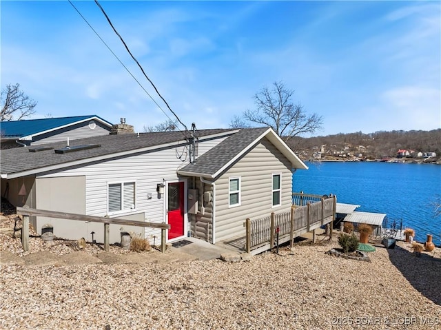 view of front facade featuring a shingled roof and a water view