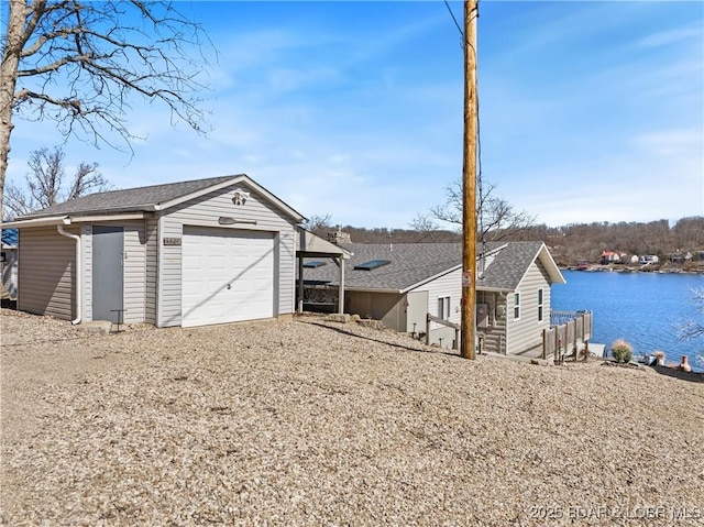 detached garage featuring a water view and driveway