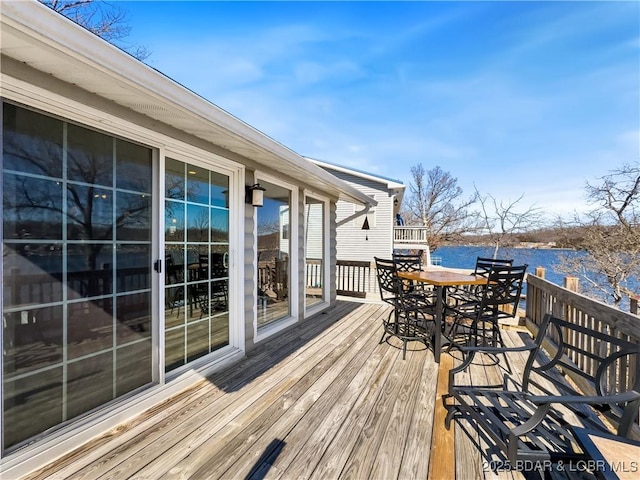 wooden deck with outdoor dining area and a water view