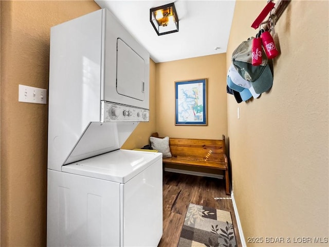 washroom featuring laundry area, baseboards, stacked washing maching and dryer, and wood finished floors