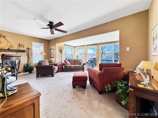 carpeted living room featuring a ceiling fan and a fireplace