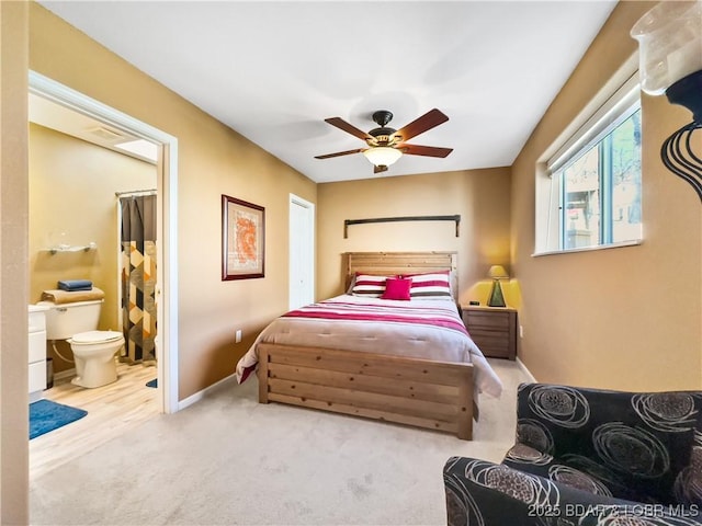 bedroom featuring carpet floors, ceiling fan, ensuite bath, and baseboards