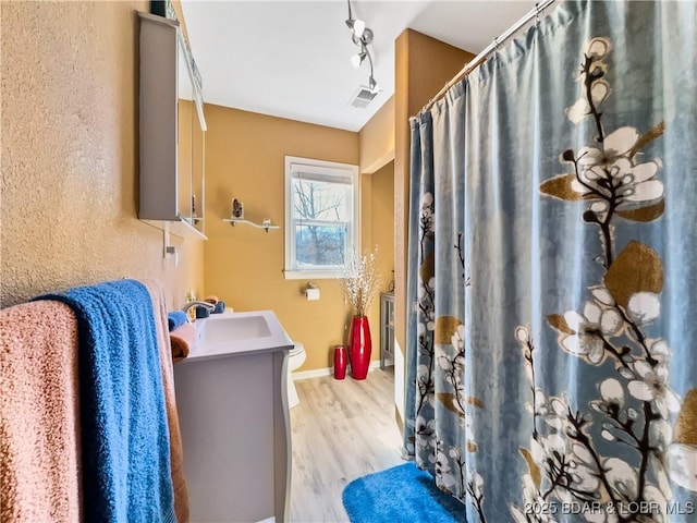 full bathroom with toilet, wood finished floors, vanity, visible vents, and baseboards