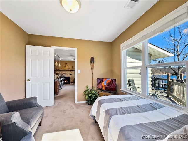 bedroom featuring light colored carpet, visible vents, a fireplace, and baseboards