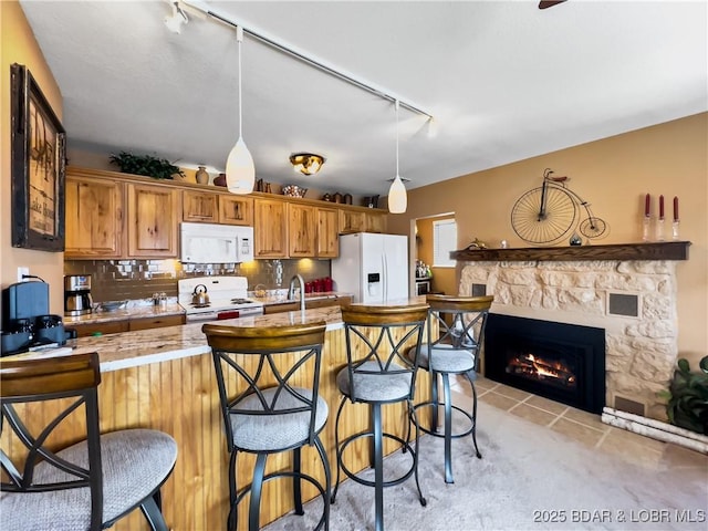 kitchen with a fireplace, a breakfast bar area, hanging light fixtures, decorative backsplash, and white appliances