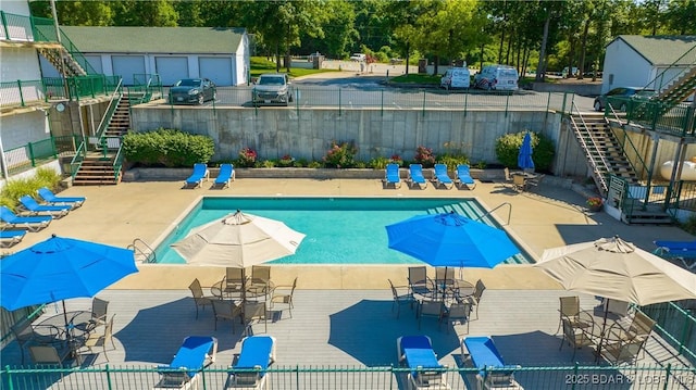 community pool featuring stairs, fence, an outbuilding, and a patio