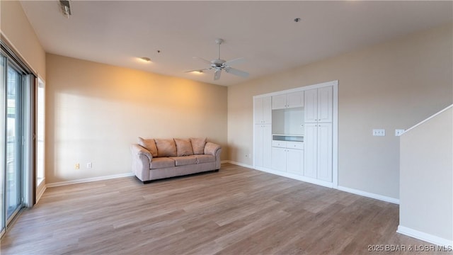 living area with light wood-type flooring, ceiling fan, and baseboards