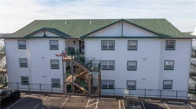 view of property with uncovered parking, fence, and stairway