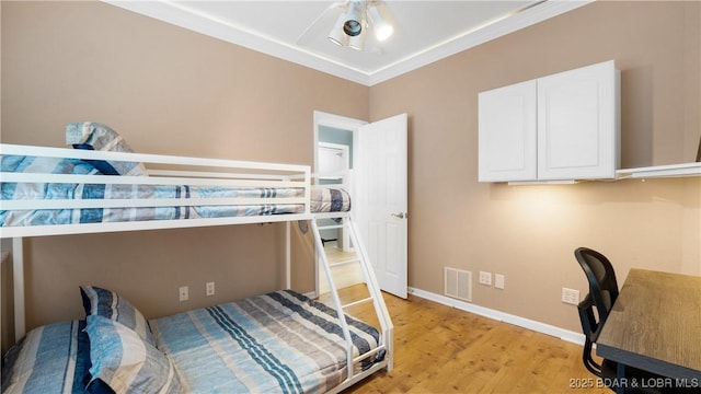 bedroom with ornamental molding, light wood-type flooring, visible vents, and baseboards