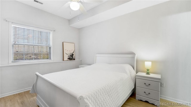 bedroom featuring a ceiling fan, wood finished floors, visible vents, and baseboards