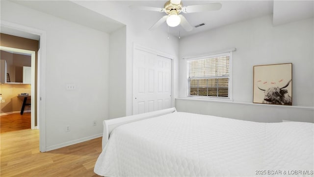 bedroom featuring light wood finished floors, a closet, visible vents, and baseboards