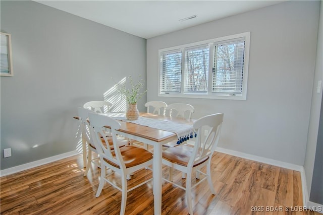 dining space featuring baseboards, visible vents, and wood finished floors