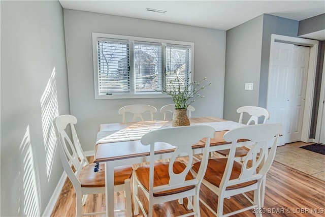 dining area featuring light wood finished floors, visible vents, and baseboards