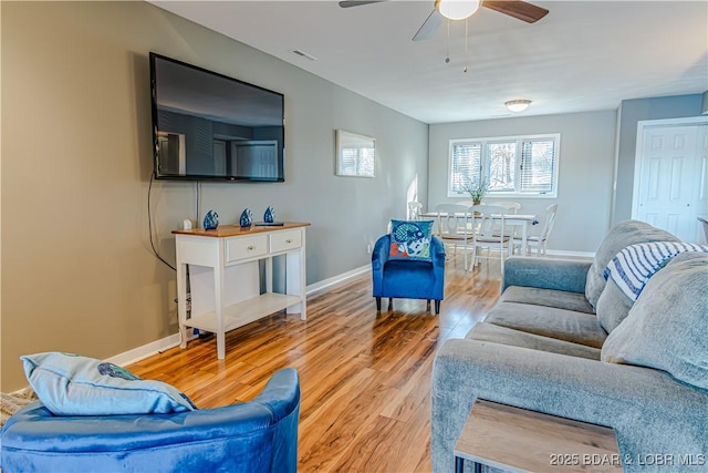 living area featuring a ceiling fan, wood finished floors, visible vents, and baseboards