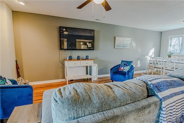 living area with ceiling fan, visible vents, baseboards, and wood finished floors