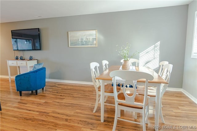 dining space featuring light wood-style flooring and baseboards