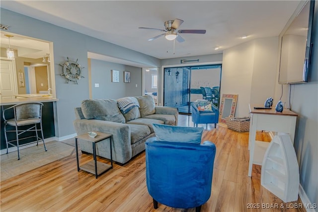 living room with ceiling fan, light wood-style flooring, and baseboards