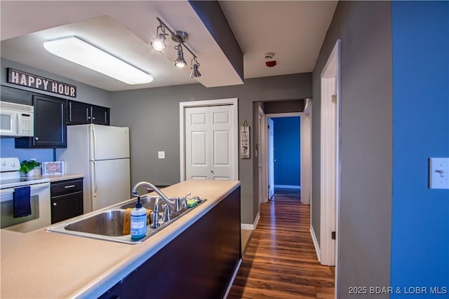 kitchen featuring light countertops, white appliances, dark wood-style flooring, and a sink