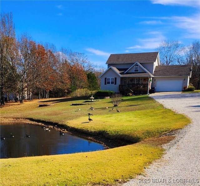 view of front of property featuring gravel driveway, an attached garage, and a front lawn