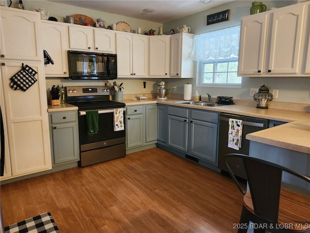 kitchen with black microwave, a sink, light wood-type flooring, stainless steel electric range, and dishwasher