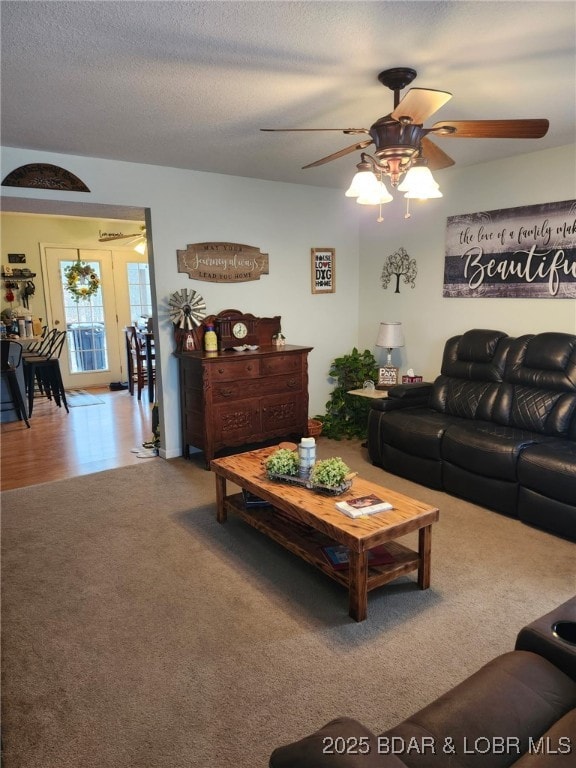 carpeted living room with ceiling fan and a textured ceiling