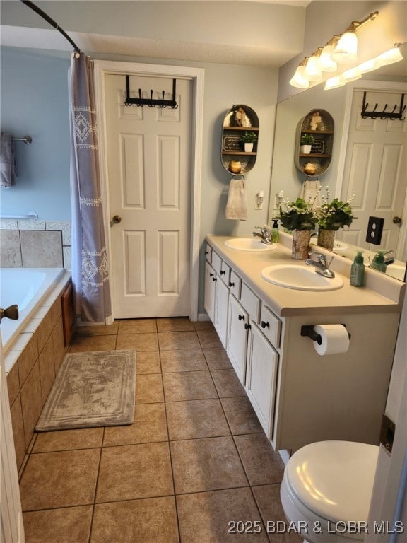 full bathroom with tiled bath, tile patterned flooring, a sink, and toilet