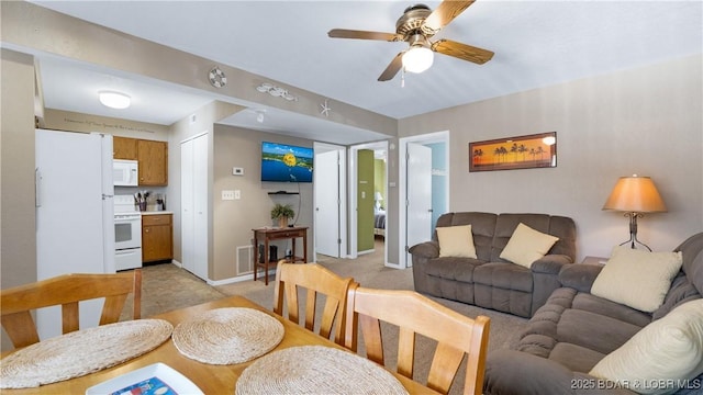 living room featuring light colored carpet, ceiling fan, and baseboards