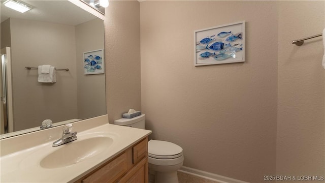 bathroom with toilet, baseboards, and vanity