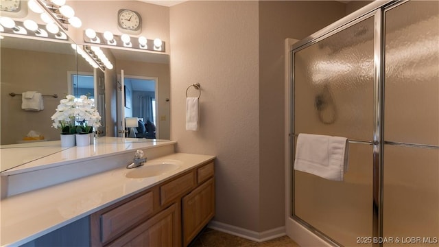 full bathroom featuring a stall shower, baseboards, and vanity