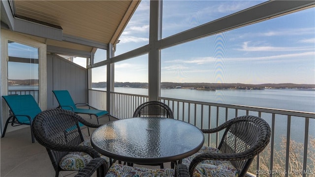 balcony featuring outdoor dining area and a water view