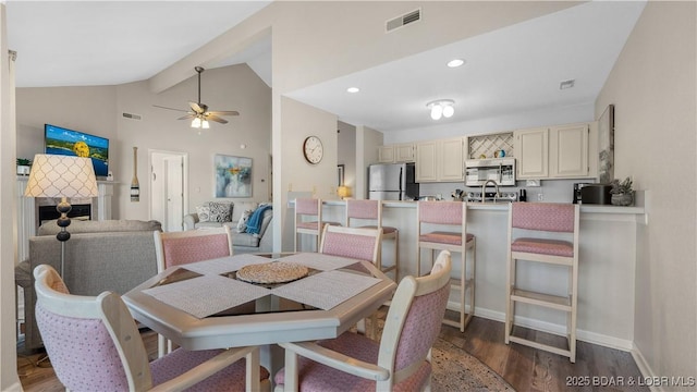 dining room with a ceiling fan, lofted ceiling, wood finished floors, a fireplace, and recessed lighting