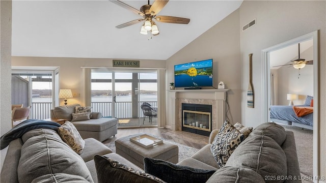 living area featuring ceiling fan, high vaulted ceiling, a fireplace, wood finished floors, and visible vents