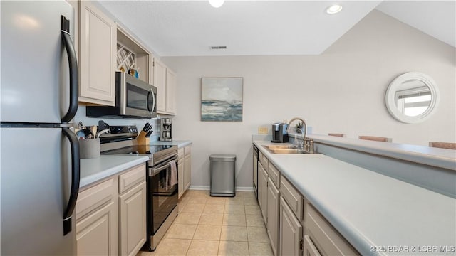 kitchen featuring light tile patterned floors, a sink, baseboards, light countertops, and appliances with stainless steel finishes