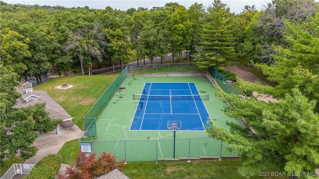 view of tennis court featuring a lawn and fence