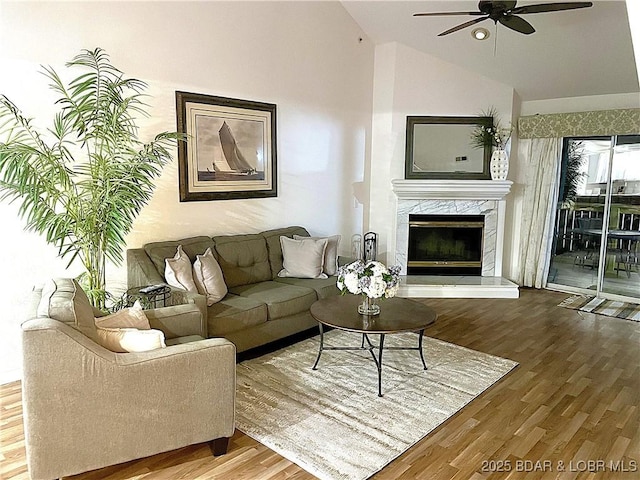 living room with a ceiling fan, lofted ceiling, a fireplace, and wood finished floors