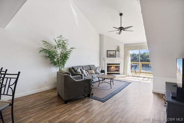 living area with high vaulted ceiling, wood finished floors, a high end fireplace, and baseboards