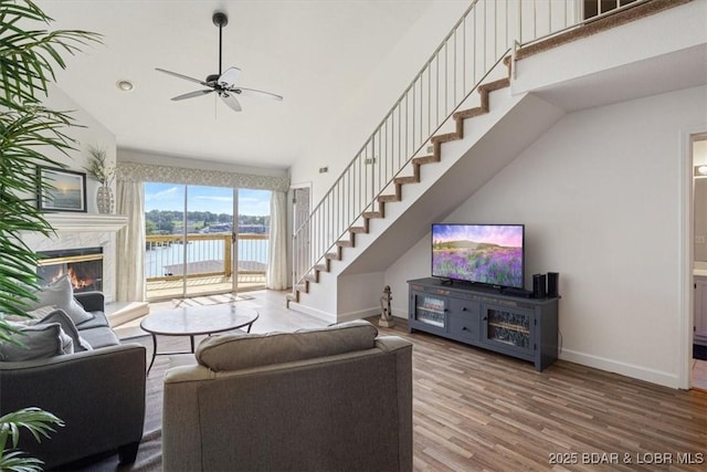 living room featuring a high end fireplace, stairway, baseboards, and wood finished floors