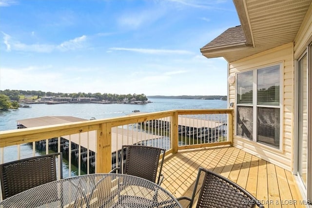 wooden terrace with a water view and outdoor dining space