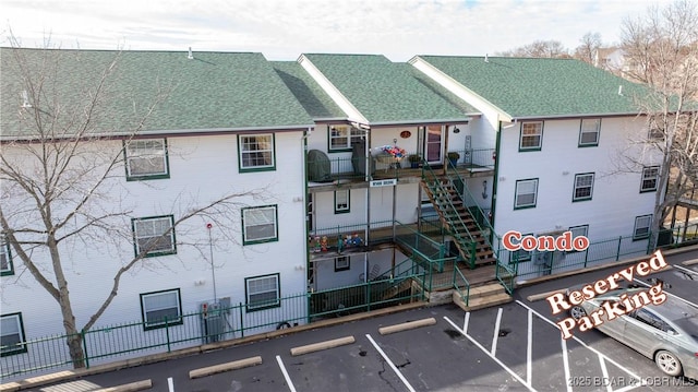 view of property with uncovered parking, fence, and stairs