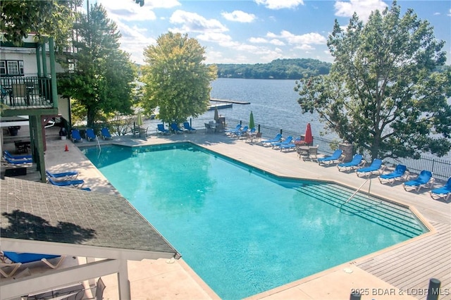 community pool with a patio area, fence, and a water view