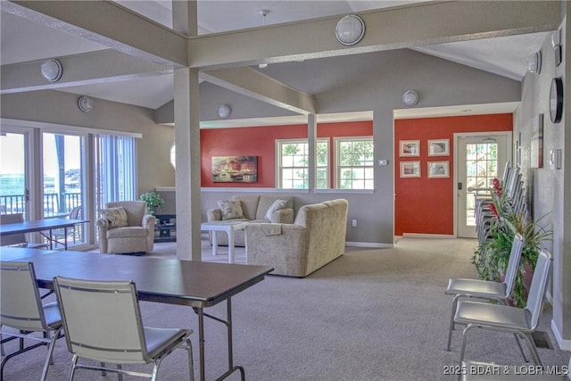 carpeted living room with plenty of natural light, vaulted ceiling with beams, and baseboards